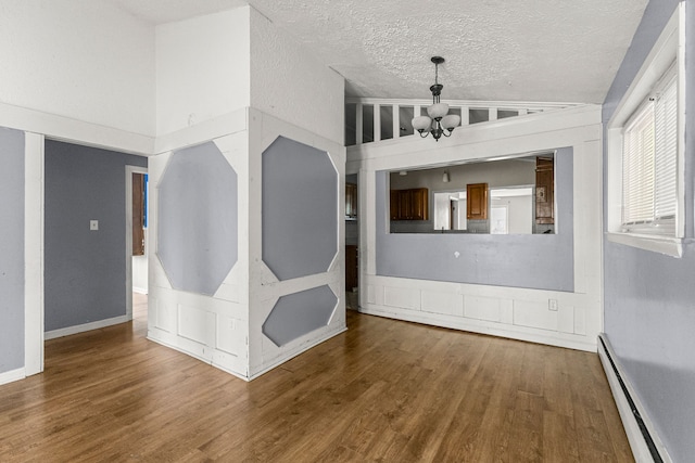 80 E Mahan Ave, Hazel Park, MI 48030 - unfurnished room featuring a baseboard heating unit, a chandelier, wood finished floors, vaulted ceiling, and a textured ceiling