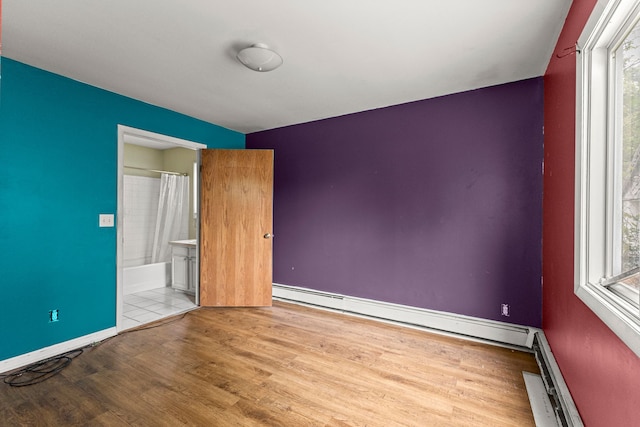 80 E Mahan Ave, Hazel Park, MI 48030 - unfurnished bedroom featuring wood finished floors, a baseboard heating unit, ensuite bath, a baseboard radiator, and baseboards