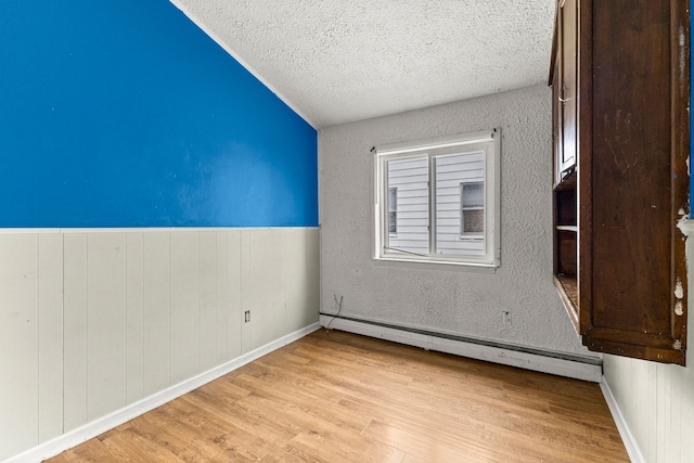 80 E Mahan Ave, Hazel Park, MI 48030 - empty room with lofted ceiling, a textured ceiling, a baseboard heating unit, light wood finished floors, and baseboards