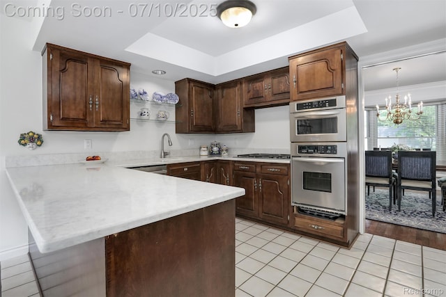 3445 Medford Dr, Troy, MI 48084 - kitchen featuring a chandelier, a peninsula, a tray ceiling, light countertops, and appliances with stainless steel finishes
