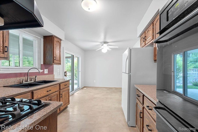 16917 Cicotte Ave, Allen Park, MI 48101 - kitchen with wall chimney range hood, black gas stovetop, a sink, freestanding refrigerator, and brown cabinets
