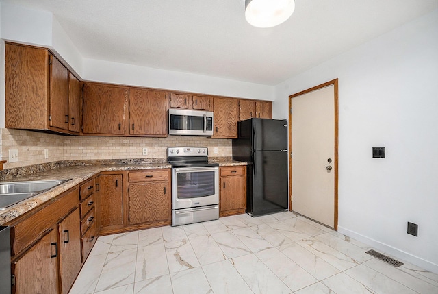 2373 Fairgrove St, Kalamazoo, MI 49009 - kitchen with stainless steel appliances, brown cabinetry, and light marble finish floors