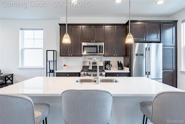 3217 Chambers W Unit 87, Wixom, MI 48393 - kitchen featuring stainless steel appliances, dark brown cabinets, a kitchen breakfast bar, an island with sink, and pendant lighting