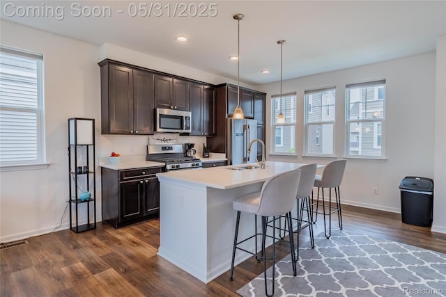 3217 Chambers W Unit 87, Wixom, MI 48393 - kitchen with stainless steel appliances, a center island with sink, dark wood-style floors, light countertops, and dark brown cabinetry