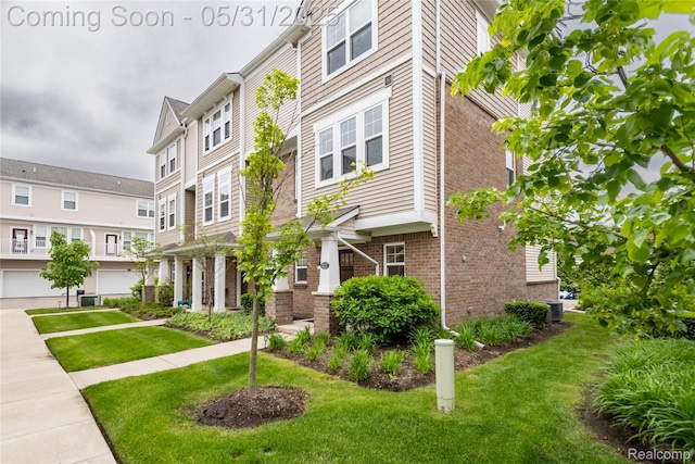 3217 Chambers W Unit 87, Wixom, MI 48393 - view of front of home featuring brick siding, a front yard, and cooling unit