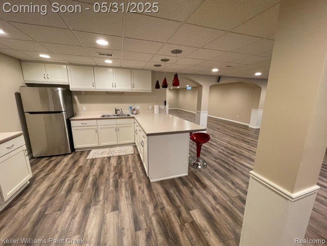 8241 Fountain View Dr, Flushing, MI 48433 - kitchen with freestanding refrigerator, a sink, a peninsula, white cabinets, and a paneled ceiling