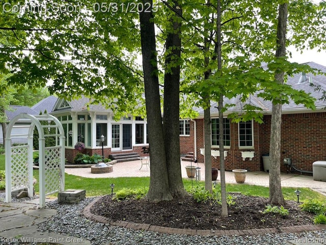 8241 Fountain View Dr, Flushing, MI 48433 - rear view of house with brick siding, a sunroom, a patio area, and entry steps
