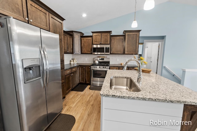 11648 Everette Ave, Allendale, MI 49401 - kitchen featuring stainless steel appliances, a sink, vaulted ceiling, tasteful backsplash, and light wood-type flooring