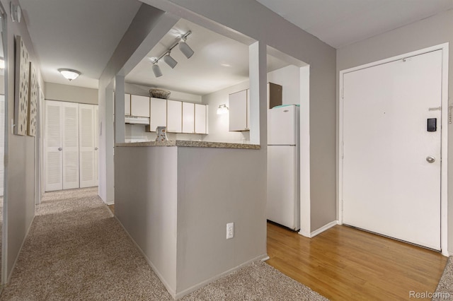 930 Village Green Ln, Waterford, MI 48328 - kitchen featuring freestanding refrigerator, white cabinets, under cabinet range hood, and baseboards