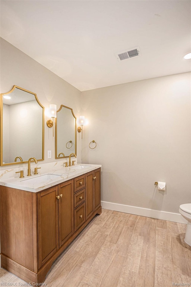 6400 N Seymour Rd, Flushing, MI 48433 - full bath featuring wood finished floors, baseboards, toilet, and double vanity