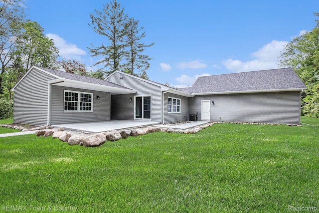 6400 N Seymour Rd, Flushing, MI 48433 - rear view of property featuring a patio area, a lawn, and roof with shingles