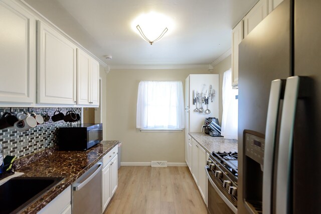 24690 Annapolis St, Dearborn Heights, MI 48125 - kitchen featuring appliances with stainless steel finishes, light wood-style flooring, tasteful backsplash, white cabinetry, and ornamental molding
