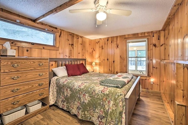 4290 Clark St, Lewiston, MI 49756 - bedroom with a textured ceiling, wooden walls, light wood-style floors, ceiling fan, and beam ceiling