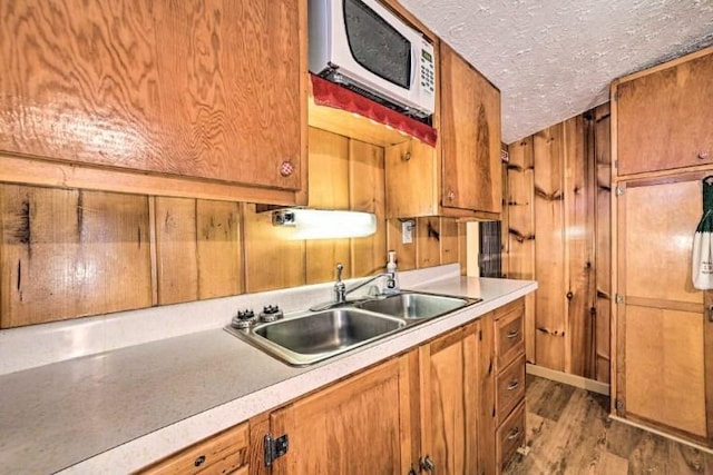 4290 Clark St, Lewiston, MI 49756 - kitchen with a sink, white microwave, brown cabinets, light countertops, and wood finished floors