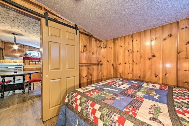 4290 Clark St, Lewiston, MI 49756 - bedroom featuring a textured ceiling, wood walls, wood finished floors, and a barn door