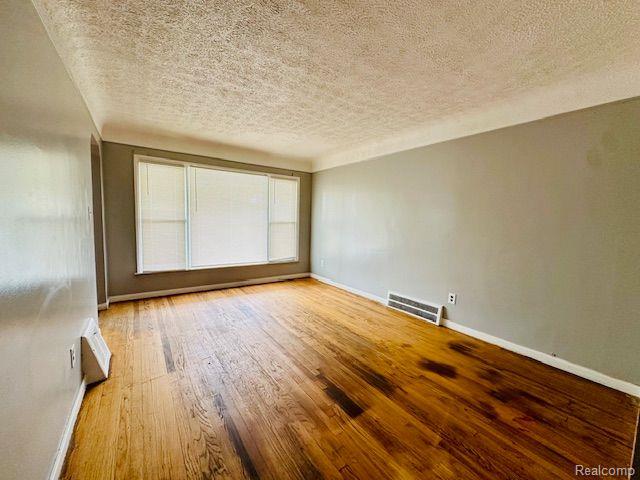 20250 Winthrop St, Detroit, MI 48235 - unfurnished room with a textured ceiling, baseboards, and wood finished floors