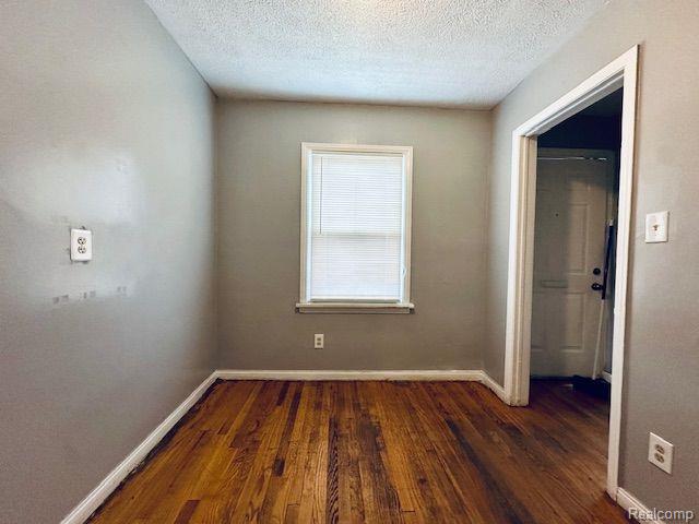 20250 Winthrop St, Detroit, MI 48235 - unfurnished room with wood finished floors, baseboards, and a textured ceiling