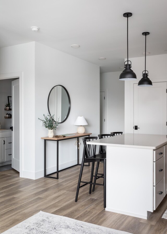222 E State St, Traverse City, MI 49684 - kitchen featuring light wood finished floors, light countertops, pendant lighting, baseboards, and white cabinetry