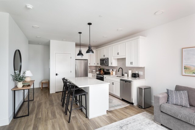 222 E State St, Traverse City, MI 49684 - kitchen featuring appliances with stainless steel finishes, light wood-style floors, a kitchen breakfast bar, light countertops, and white cabinetry