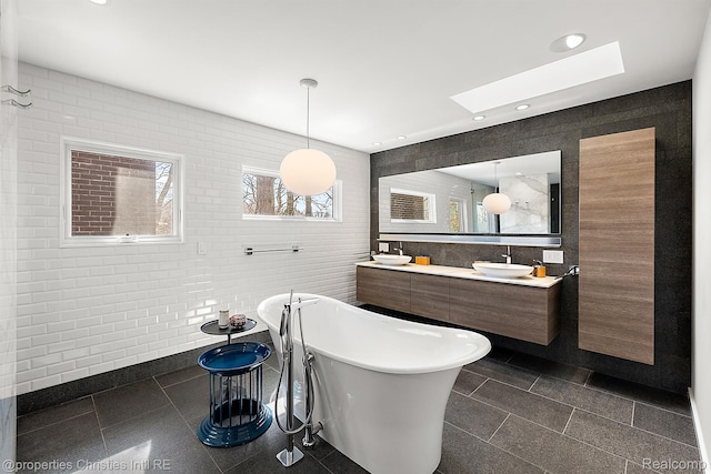 7371 Lindenmere Dr, Bloomfield Hills, MI 48301 - bathroom featuring tile walls, a freestanding tub, a skylight, plenty of natural light, and double vanity