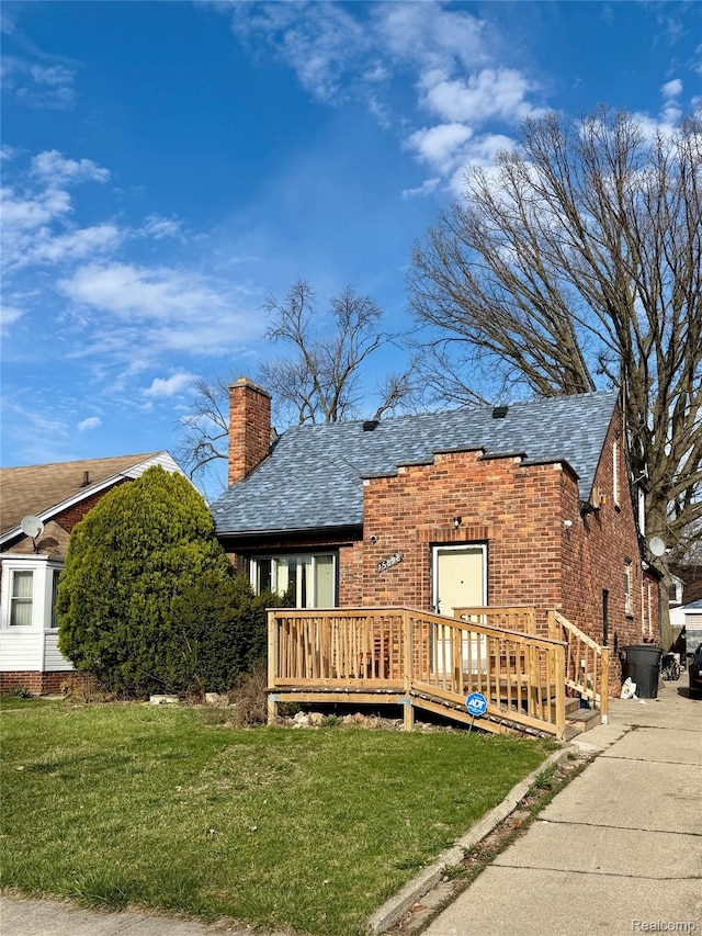 15898 Asbury Park, Detroit, MI 48227 - view of front facade with a chimney, a wooden deck, a front yard, brick siding, and roof with shingles