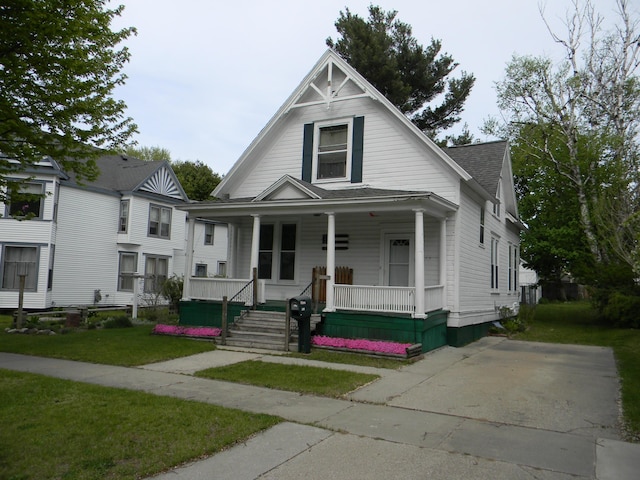 306 N Rowe St, Ludington, MI 49431 - view of front of property with covered porch, a front lawn, and roof with shingles