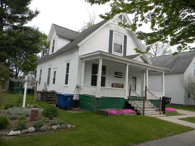 306 N Rowe St, Ludington, MI 49431 - view of front of property featuring a porch, a shingled roof, and a front lawn