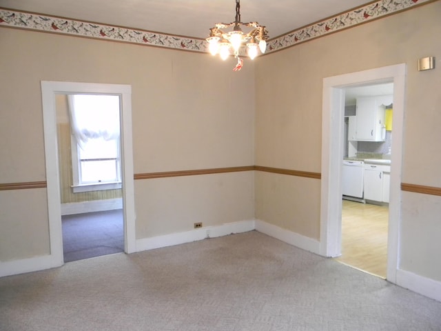 306 N Rowe St, Ludington, MI 49431 - empty room with light colored carpet, a chandelier, and baseboards