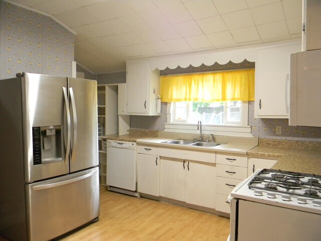 306 N Rowe St, Ludington, MI 49431 - kitchen featuring white appliances, a sink, wallpapered walls, light countertops, and light wood-style flooring