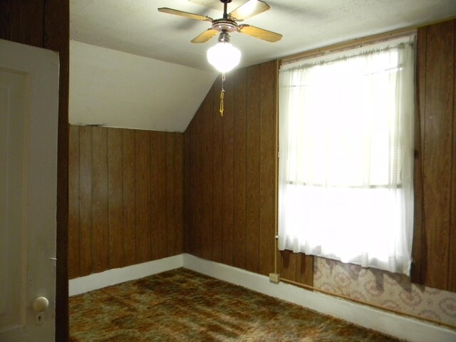 306 N Rowe St, Ludington, MI 49431 - bonus room featuring wooden walls, dark carpet, ceiling fan, and lofted ceiling