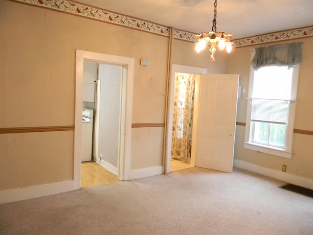 306 N Rowe St, Ludington, MI 49431 - carpeted spare room featuring a chandelier, baseboards, and washer / dryer