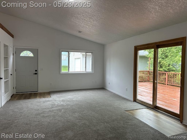 5399 Brobeck St, Flint, MI 48532 - carpeted empty room with vaulted ceiling, a textured ceiling, baseboards, and french doors
