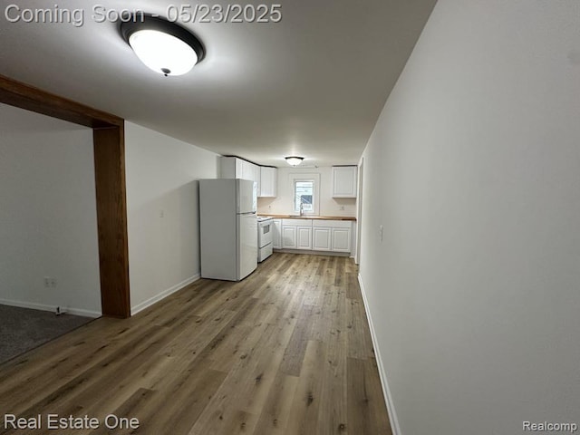5399 Brobeck St, Flint, MI 48532 - kitchen featuring white appliances, white cabinetry, light wood-style floors, baseboards, and a sink