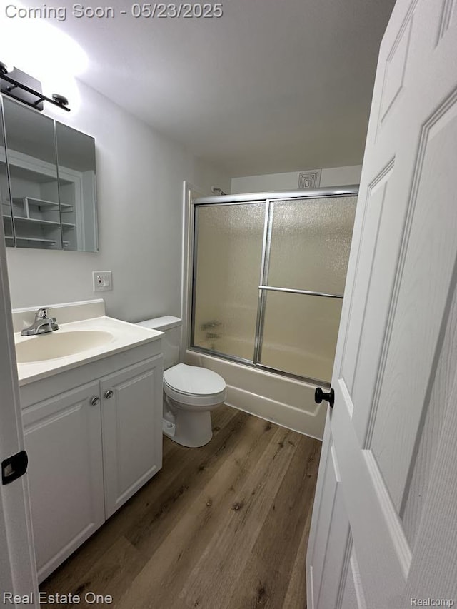 5399 Brobeck St, Flint, MI 48532 - bathroom featuring wood finished floors, vanity, toilet, and combined bath / shower with glass door