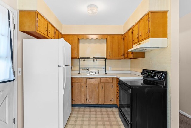 612 E 3rd St, Flint, MI 48503 - kitchen with freestanding refrigerator, black electric range, under cabinet range hood, light floors, and a sink