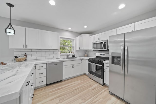 5726 Joshua Dr, Eaton Rapids, MI 48827 - kitchen with stainless steel appliances, a sink, white cabinets, light wood-style floors, and recessed lighting