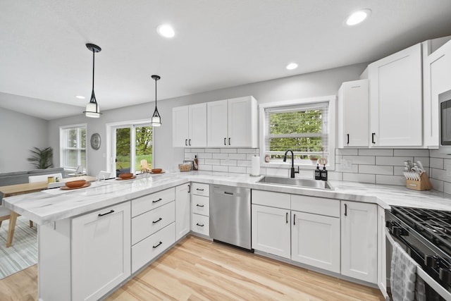 5726 Joshua Dr, Eaton Rapids, MI 48827 - kitchen with appliances with stainless steel finishes, a sink, a peninsula, decorative backsplash, and white cabinetry