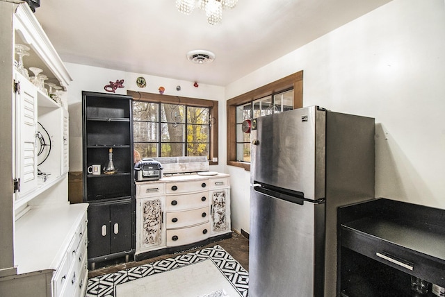 4491 S Jackson Rd, Jackson, MI 49201 - kitchen featuring freestanding refrigerator, light countertops, a chandelier, and white cabinetry