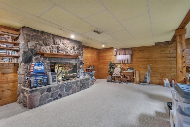 3460 Sears Rd, Horton, MI 49246 - carpeted living area with wooden walls, a drop ceiling, and a stone fireplace