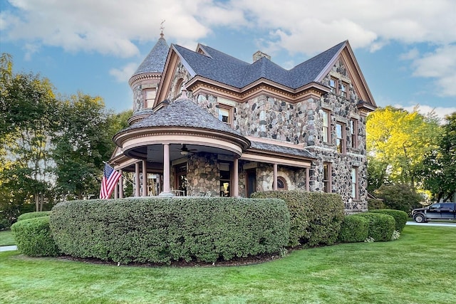 303 S State Ave, Alpena, MI 49707 - rear view of house featuring stone siding, a yard, ceiling fan, and a high end roof