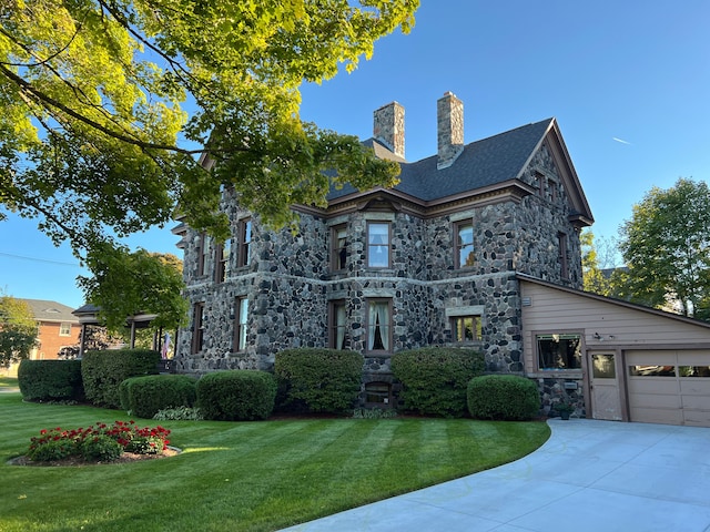 303 S State Ave, Alpena, MI 49707 - view of front of home featuring stone siding, concrete driveway, a chimney, and a front lawn