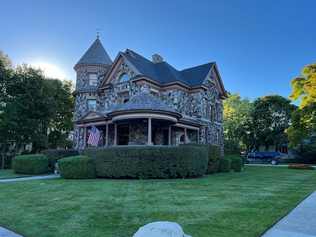 303 S State Ave, Alpena, MI 49707 - view of home's exterior with stone siding, a yard, a high end roof, and a chimney