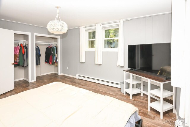 1466 Wilson Ave, Saginaw, MI 48638 - bedroom featuring baseboard heating, wood finished floors, and multiple closets
