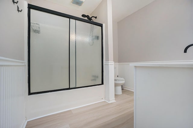 604 W Hill St, Plainwell, MI 49080 - full bath with wood finished floors, toilet, a wainscoted wall, enclosed tub / shower combo, and a decorative wall