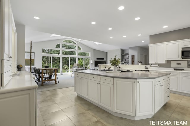 12993 144th Ave, Grand Haven, MI 49417 - kitchen featuring a skylight, stainless steel microwave, white cabinetry, vaulted ceiling, and recessed lighting