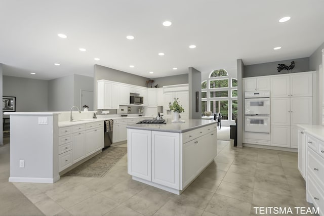 12993 144th Ave, Grand Haven, MI 49417 - kitchen featuring black dishwasher, white double oven, stainless steel microwave, gas cooktop, and white cabinetry