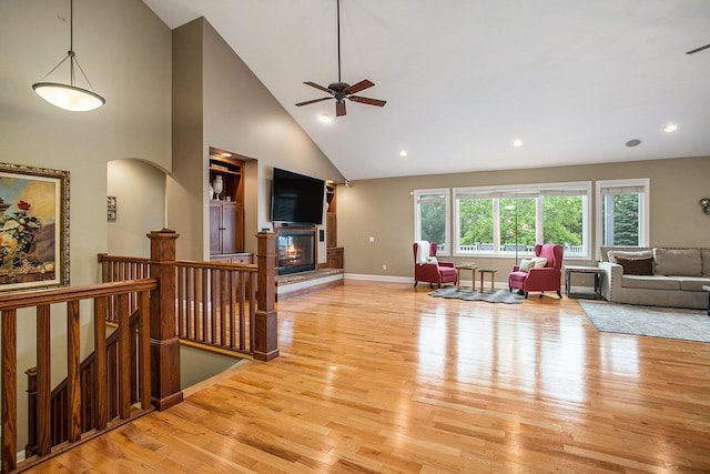 7522 S 10th St, Kalamazoo, MI 49009 - living room featuring light wood-style floors, a glass covered fireplace, a ceiling fan, high vaulted ceiling, and baseboards