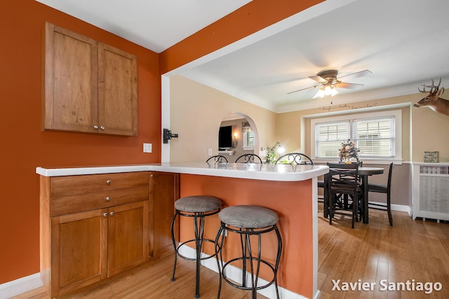 429 Van Allen St SE, Wyoming, MI 49548 - kitchen featuring a kitchen breakfast bar, a ceiling fan, a peninsula, light wood finished floors, and brown cabinetry