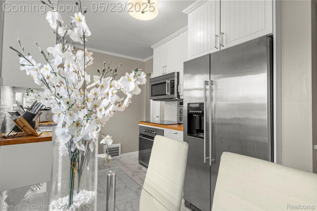 3346 Westpoint St, Dearborn, MI 48124 - kitchen featuring appliances with stainless steel finishes, crown molding, marble look tile flooring, white cabinets, and wood counters