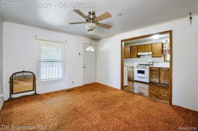 8114 Wilson Rd, Otisville, MI 48463 - kitchen with white range with gas stovetop, brown cabinetry, under cabinet range hood, crown molding, and ceiling fan